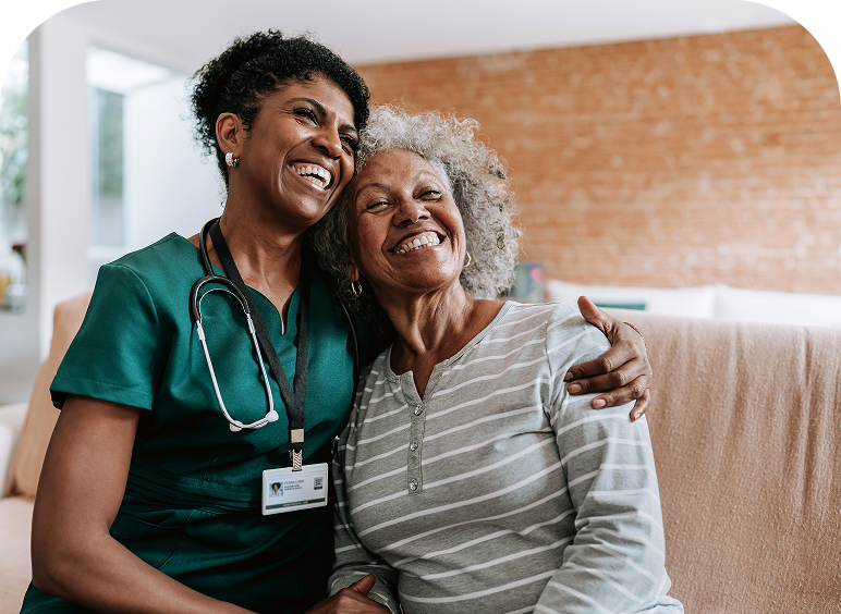 Nurse hugging elderly woman, both smiling.