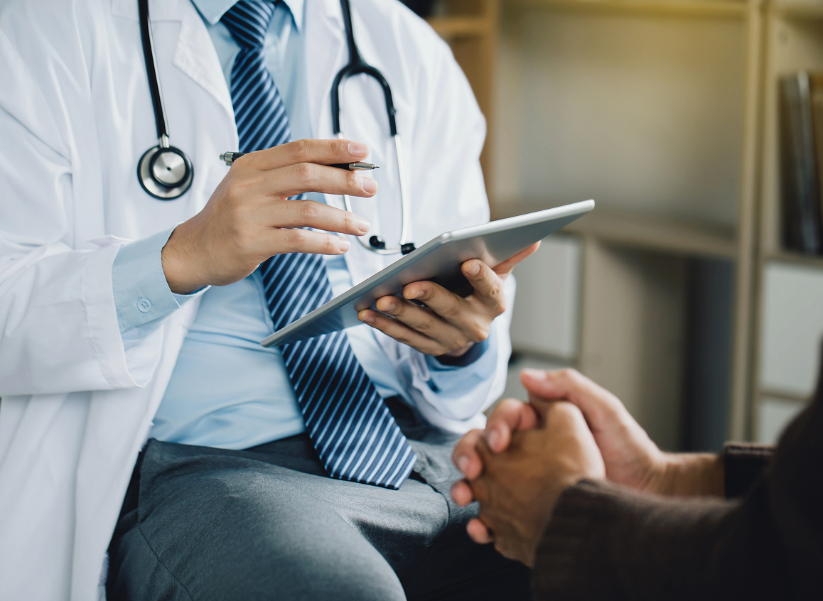 Doctor consulting patient with digital tablet.